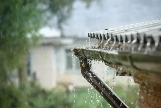 Regen-Dach Regenwasser läuft von einem Flachdach mit Dachrinne ab.