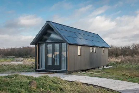 Ein modernes Singlehaus als feststehende Wohnlösung im Vergleich zum mobilen Tiny House, das Flexibilität beim Wohnort bietet.